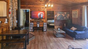 A wooden interior with a television, bookshelves, a sofa, and a fireplace. - Rustic River Front Cottage Cozy*Kayaks*Hot Tub*Games (Kawartha Lakes)