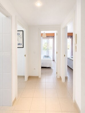 A hotel room with a bed, a bathroom, and a hallway leading to another room.