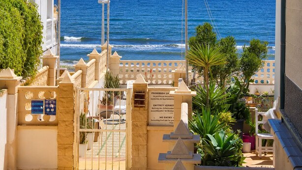 Una entrada protegida con vista al mar, una piscina y un balcón con plantas.