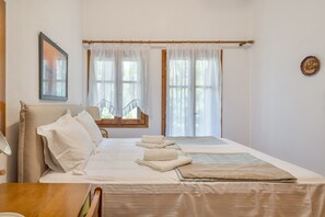 A bedroom with a bed, pillows, a bedside table, a window with curtains, and a wall-mounted picture. - Villa Anty Holiday Home in Sani, Chalkidiki—Private Terrace & Pine Forest Views (Sane)