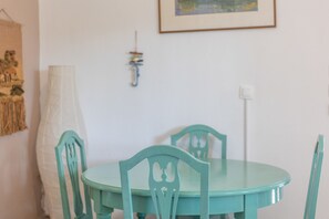 A dining table with chairs, a hanging light fixture, and a wall-mounted power outlet. - Villa Anty Holiday Home in Sani, Chalkidiki—Private Terrace & Pine Forest Views (Sane)