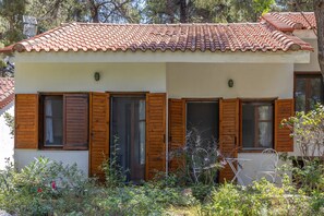 A two-story building with a tiled roof, wooden shutters on the windows, and a garden in front. - Villa Anty Holiday Home in Sani, Chalkidiki—Private Terrace & Pine Forest Views (Sane)