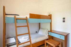Ein Stockbett mit Holzleiter, ein Schreibtisch mit Schubladen und ein kleiner Stuhl.