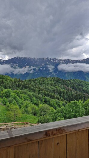 A view of a forested mountain range with a wooden railing in the foreground. - Isolated Cabin in Kichkhuldashi, Svaneti with Lake Fishing & Horse Riding (Nakra)