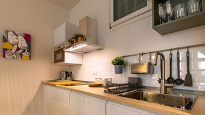 Una cucina moderna con lavello in acciaio inossidabile, cappa aspirante e piano di lavoro con bollitore e pianta.