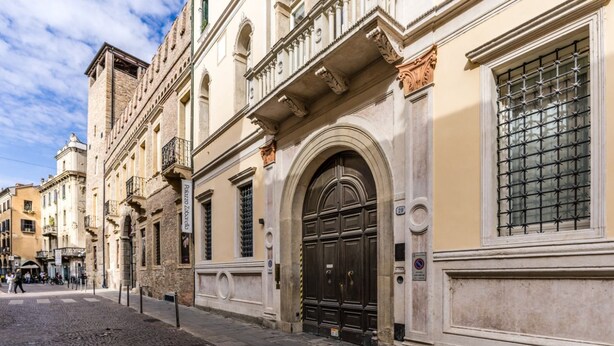 Una strada acciottolata con edifici storici, una porta nera ben visibile e un'insegna che indica un ristorante.