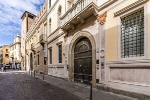 Una calle empedrada con edificios históricos, una puerta negra destacada y un letrero que indica un restaurante.