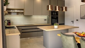 Una cocina moderna con una isla central, electrodomésticos de acero inoxidable e iluminación colgante.
