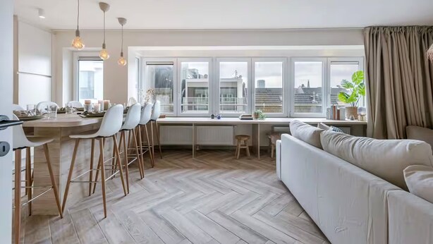 A modern kitchen with a dining area, large windows, and a view of the city. - Juan | Trendy Renovated Apartment in the Heart of Ostend | Sleeps 8 (Oostende)