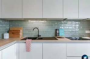 Eine moderne Küche mit weißen Schränken, einem schwarzen Wasserhahn, einer Holz-Schneidebrett und einem karierten Handtuch.