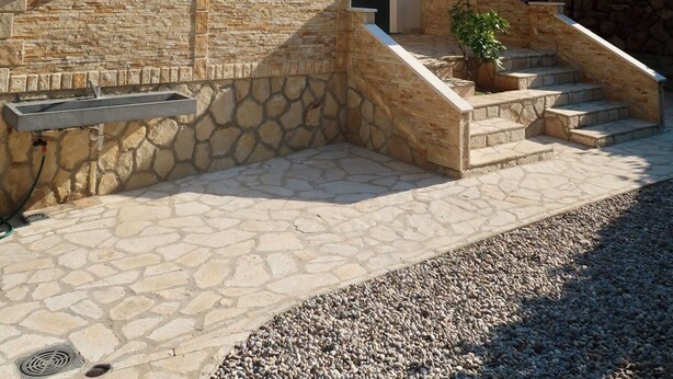 Una villa con fachada de piedra, un balcón y una escalera que lleva a la entrada.