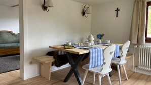 Un comedor con una mesa preparada para dos personas, una banca y un sofá al fondo.