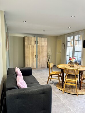 Ein modernes Wohnzimmer mit einer Couch, einem Esstisch, Stühlen und einem großen Holzschrank.