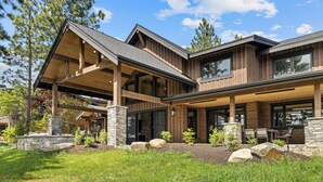 A modern two-story house with a stone foundation, wooden exterior, and a covered patio area. - Whisper Ridge - Luxury 5 BD - Walk to Social Village (CLE ELUM)