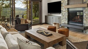 A modern living room with a fireplace, large windows, and a flat-screen TV. - Whisper Ridge - Luxury 5 BD - Walk to Social Village (CLE ELUM)