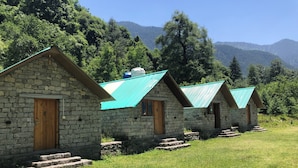Un hilera de casas de piedra con tejados verdes, puertas de madera y escalones que llevan a la entrada.