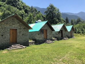 Un hilera de casas de piedra con tejados verdes, puertas de madera y escalones que llevan a la entrada.