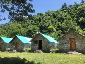 Une rangée de maisons en pierre aux toits turquoise, se dressant sur fond d’une forêt dense.