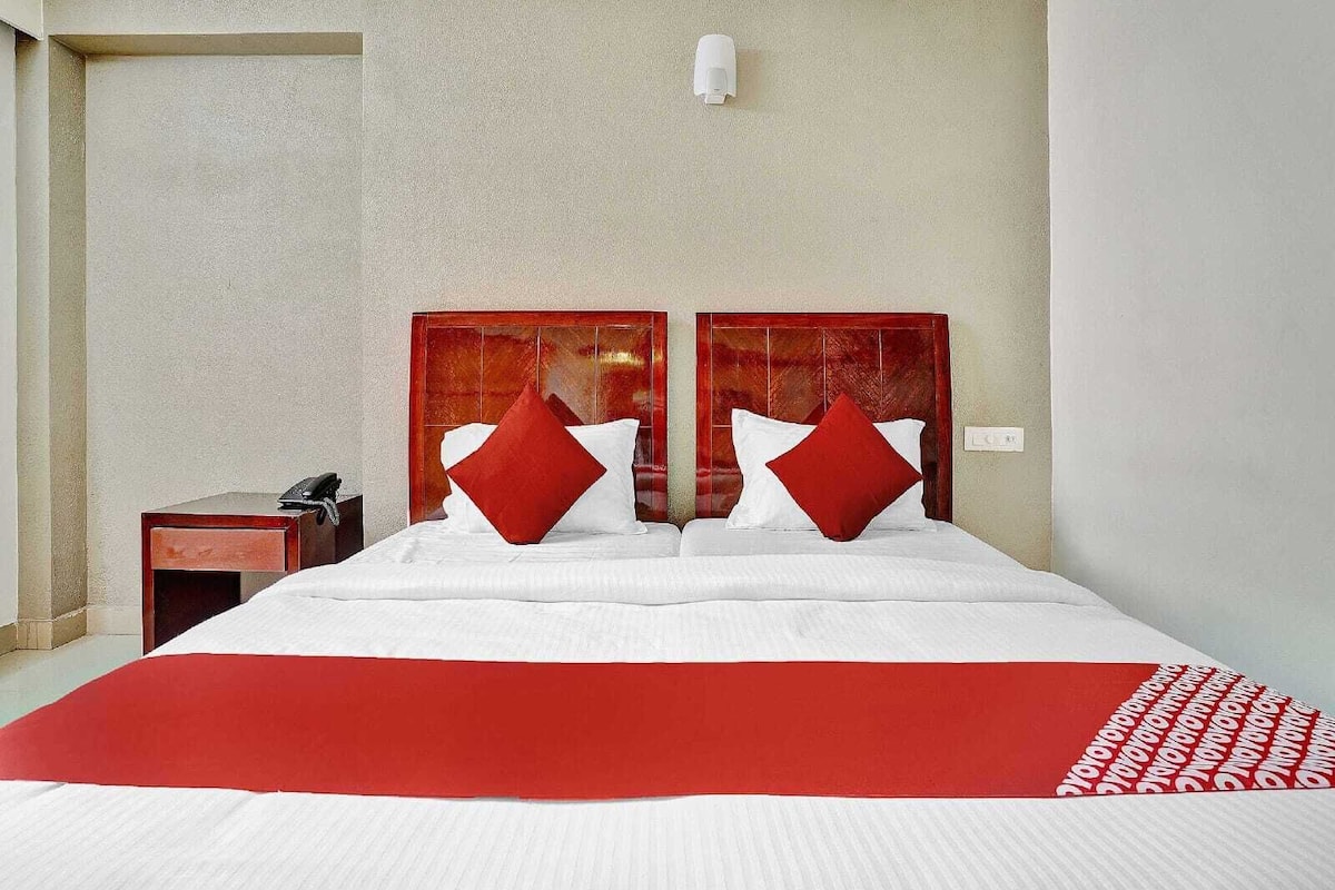 Una habitación de hotel con cama, mesita de noche y lámpara de pared.