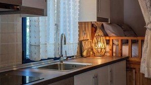 Une cuisine moderne équipée d’un évier, de placards et d’une fenêtre ornée de rideaux légers.