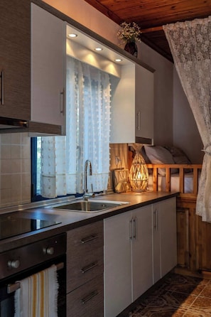 Eine moderne Küche mit Spüle aus Edelstahl, Holzschränken und einem Fenster mit durchsichtigen Vorhängen.