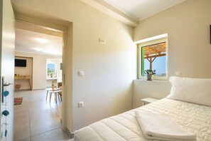 Une chambre avec un lit, une fenêtre donnant sur un beau paysage, une petite table et une chaise.