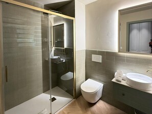 Ein modernes Badezimmer mit einer Glaskabine zur Dusche, einer weißen Toilette und einem Waschbecken mit Spiegel darüber.