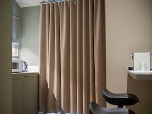 A room with a beige curtain, a microwave, a chair, and a small table with a glass. - Deluxe Apartment With Balcony (Alicante)
