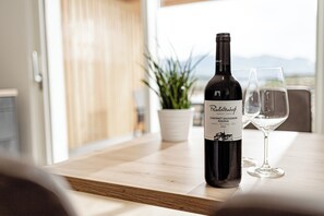 Eine Weinflasche und ein Glas auf einem Holztisch mit Blick auf die Berge im Hintergrund.