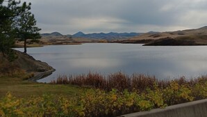 A lake with a road in the foreground, surrounded by hills and a cloudy sky.