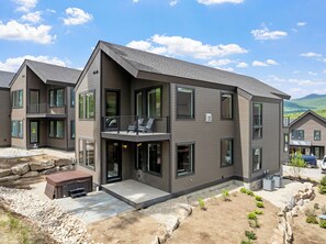 Ein modernes, zweistöckiges Haus mit Balkon, Terrasse und einer Steinmauer.