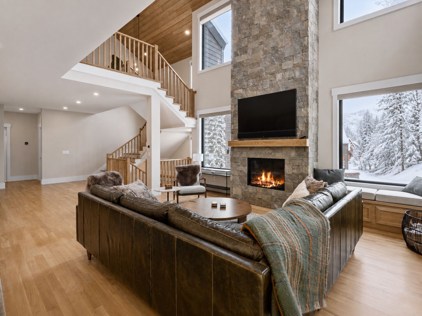 A spacious living room with a fireplace, a large sofa, a coffee table, and a staircase leading to an upper level.