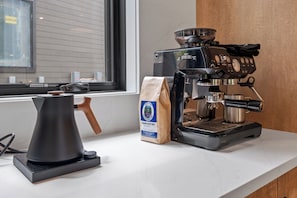 Eine Kaffeemaschine, eine Packung Kaffeebohnen und eine Kaffeekanne auf einer Arbeitsplatte.