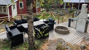 Une terrasse dotée de mobilier d’extérieur, d’un barbecue et offrant une vue sur un bâtiment rouge.