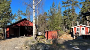 Un bâtiment rouge avec une entrée couverte, un petit abri et une cabane dotée d’un porche.