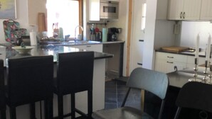 Une cuisine moderne dotée d’un îlot central, de tabourets de bar et d’un coin repas avec des chaises.