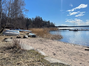A lakeside area with boats, a dock, and a forested background.