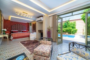 Un dormitorio con cama, escritorio, silla, sofá y vista a una piscina al aire libre.
