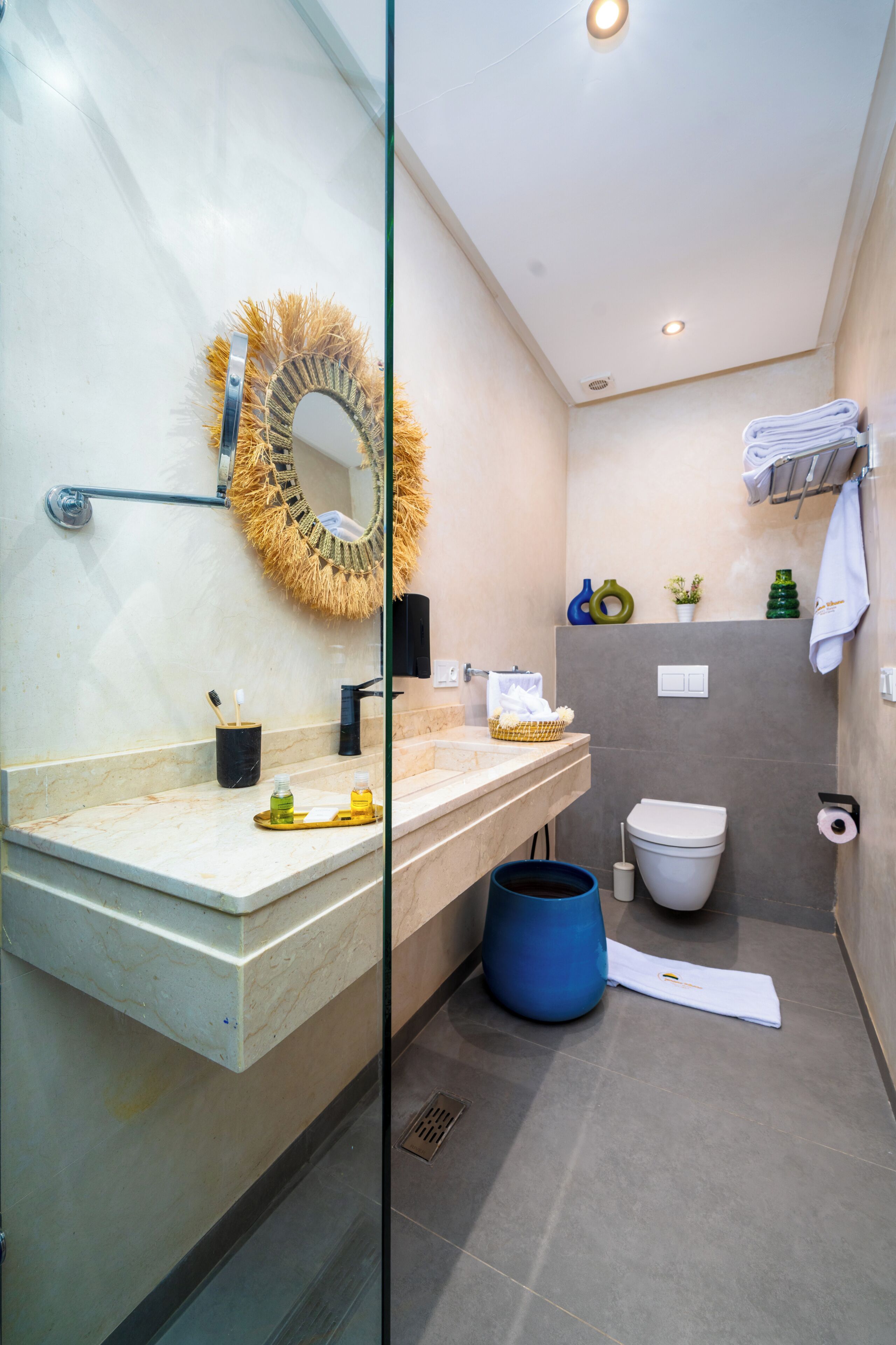 A modern bathroom with a glass partition, a vanity with a mirror, a toilet, and a shower area.