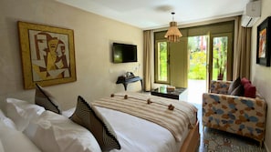 A hotel room with a bed, a television, a desk, a chair, and a painting on the wall. - Jnane Rihane Marrakech (Marrakech)