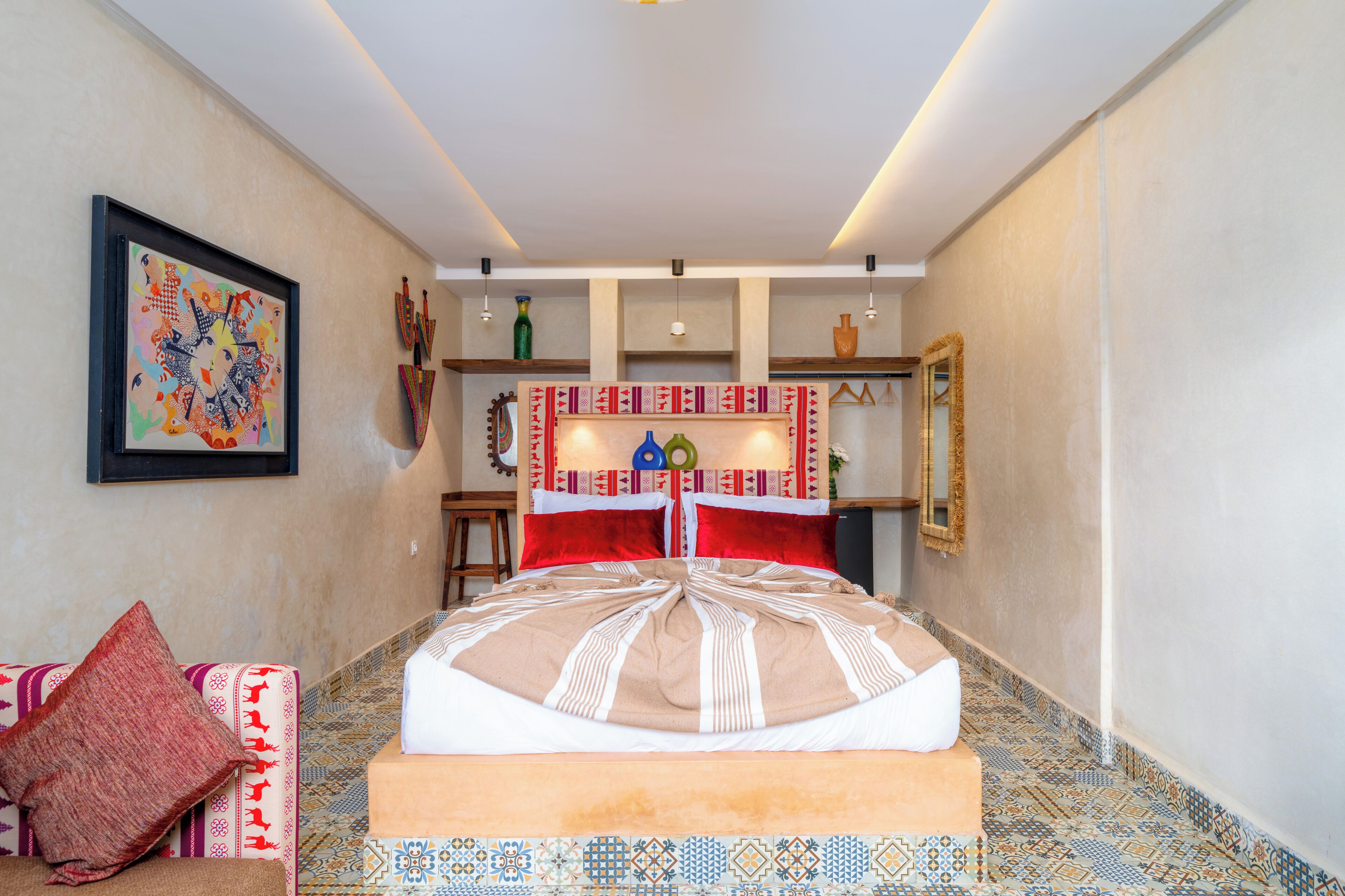A bedroom with a bed, a colorful painting, and a patterned floor.
