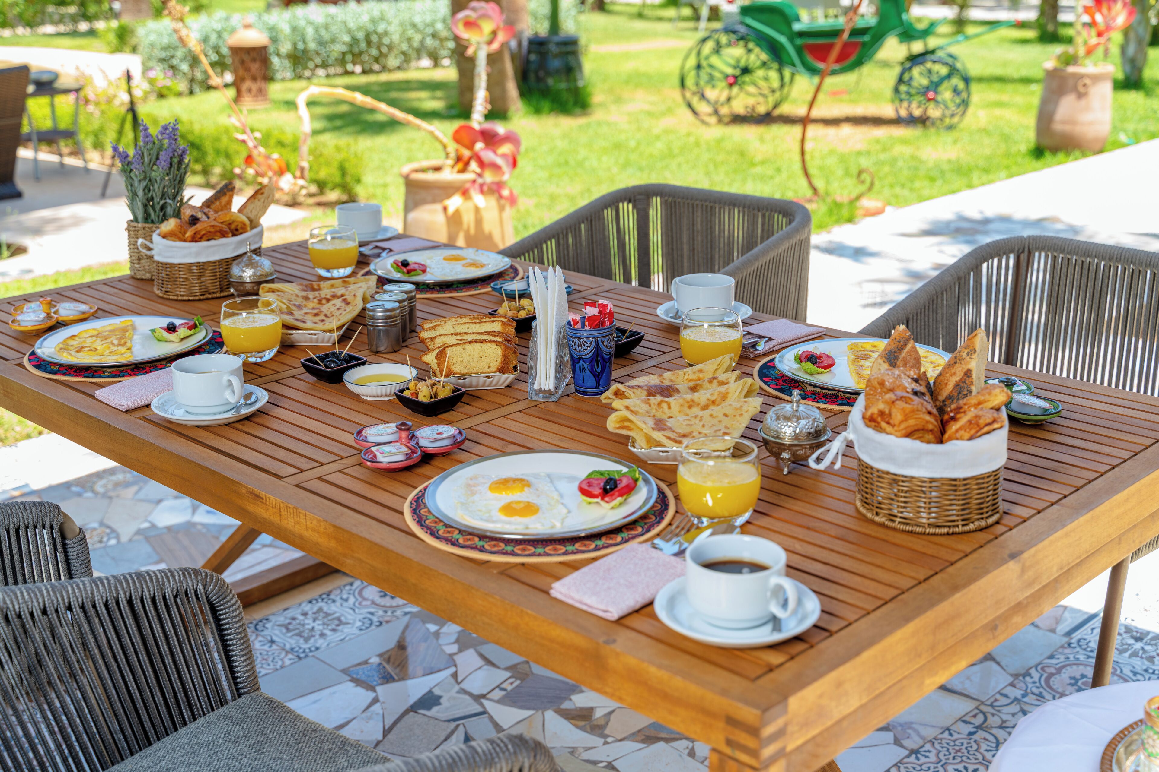 An outdoor dining table with breakfast items, wicker baskets, and outdoor chairs.