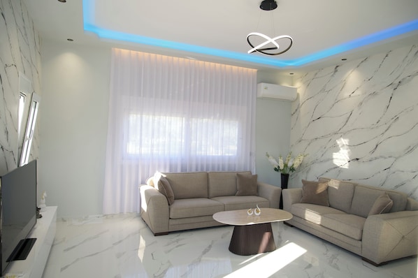A modern living room with a sofa, a coffee table, and a TV. - Merdanai Villa (64C3+69, Archaggelos 851 02, Greece)