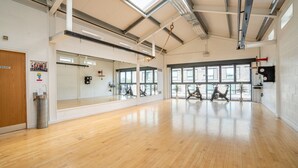 A spacious gym with wooden floors, large windows, and exercise bikes. - Swift Apartments - Apartment 6 with Free Gym Access (York)