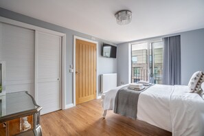 Ein Schlafzimmer mit einem Bett, einem Fernseher, einer Holztür und einem Fenster mit Blick.