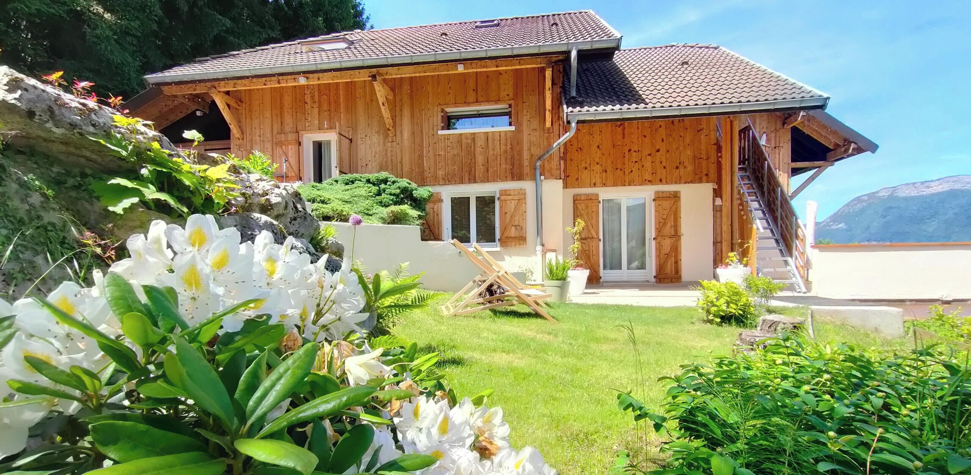 A wooden chalet with a sloped roof, a front porch, and a staircase leading to the entrance.