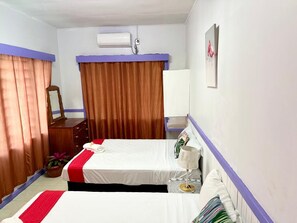 Ein Hotelzimmer mit zwei Betten, einem Schminktisch, einem Spiegel, einer Klimaanlage und einem Fenster mit Vorhängen.