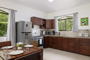 A modern kitchen with wooden cabinets, stainless steel appliances, and a dining area with a table set for two.