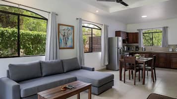 A modern living room with a grey sofa, wooden coffee table, and a dining area with a wooden table and chairs.