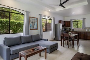 Una sala moderna con un sofá gris, una mesa de centro de madera y una zona de comedor con una mesa y sillas de madera.